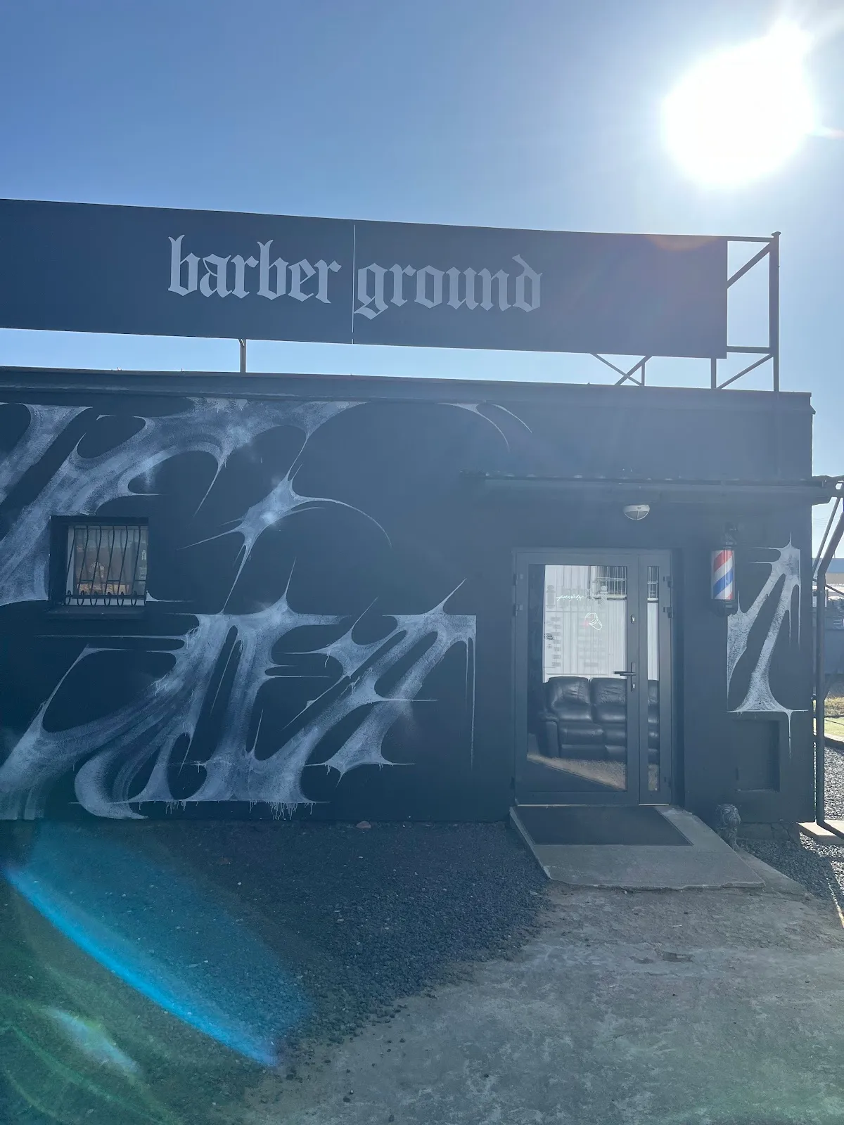 Elewacja Barberground w Suchym Lesie: szyld „barber ground” i mural przy wejściu