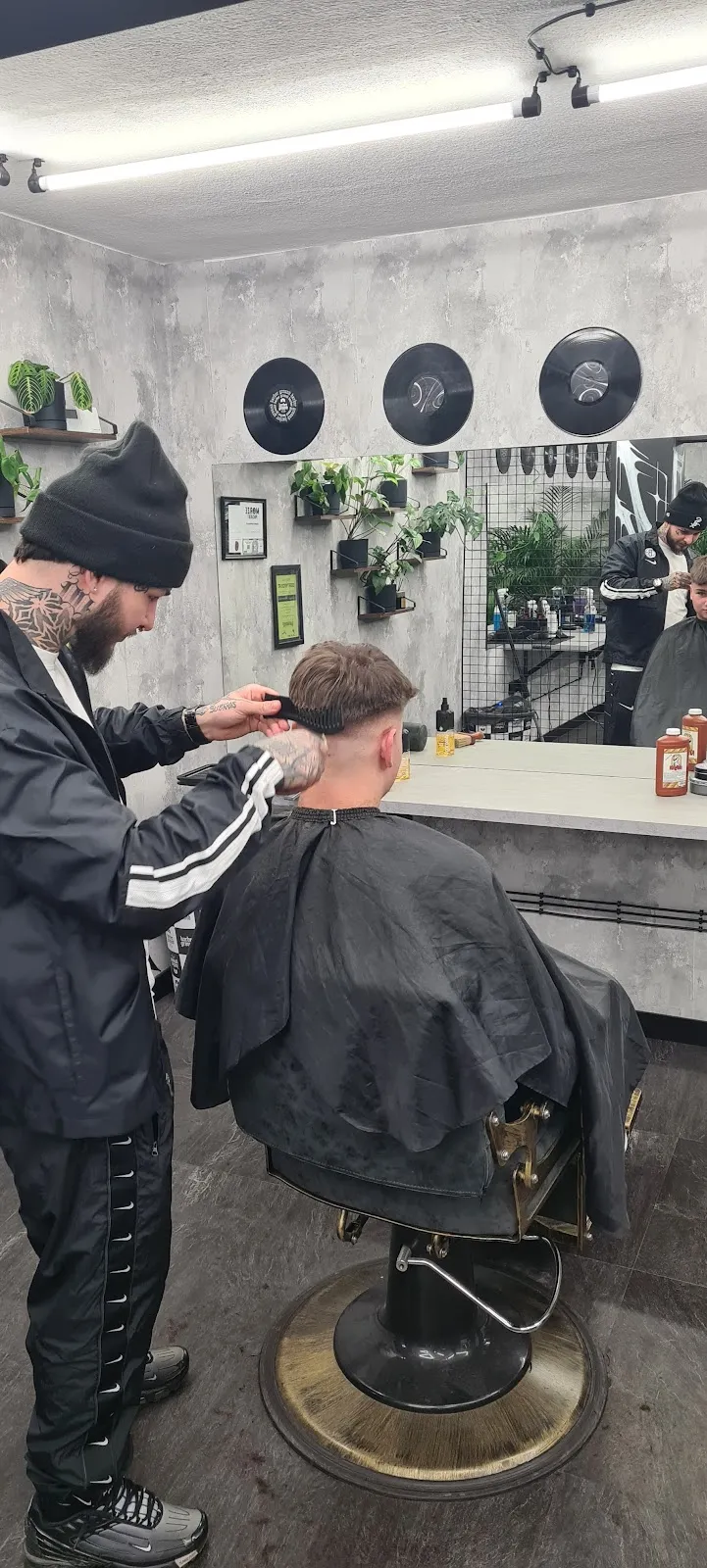 Barber w Barberground strzyże klienta maszynką przy stanowisku