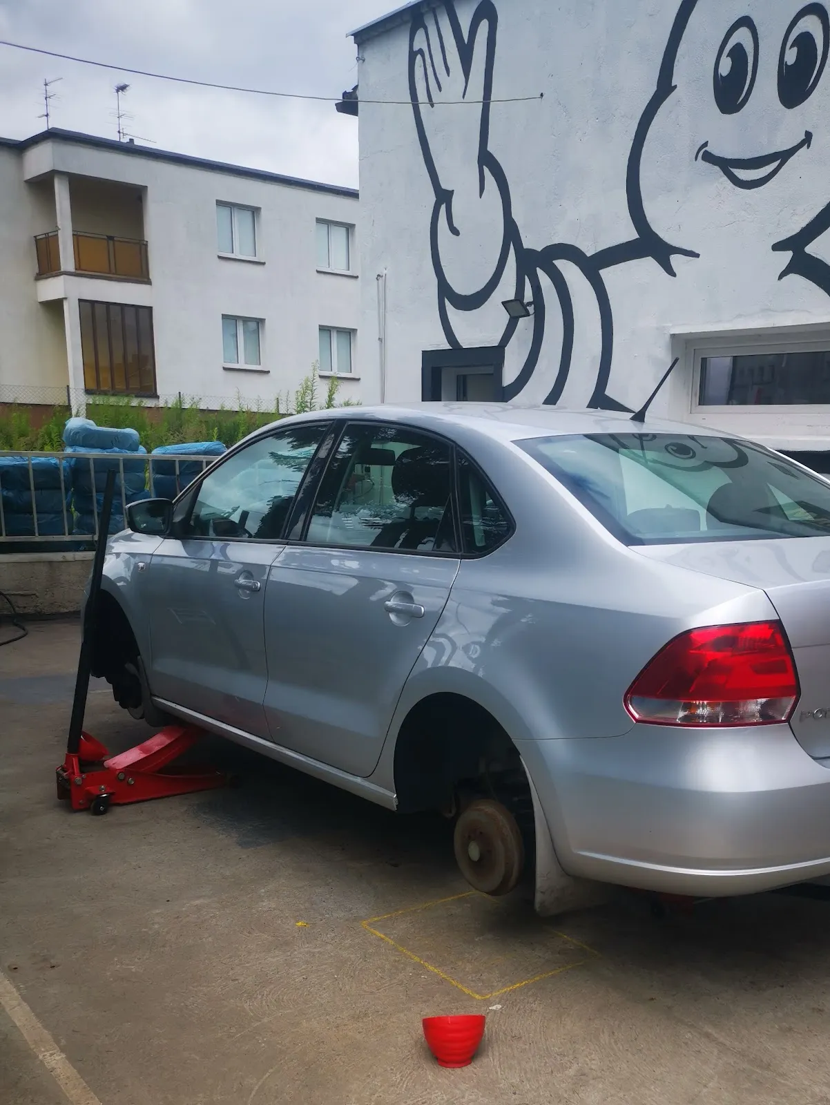 Auto na podnośniku ze zdjętym kołem przed muralem Michelin